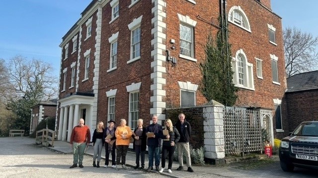 A group of event attendees posing in front of Trafford Hall